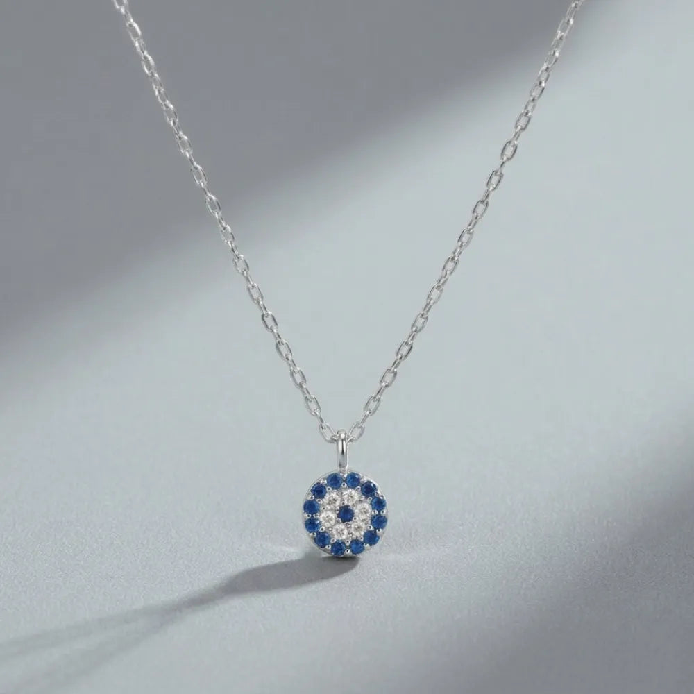 Ett delikat silverhalsband med en cirkulär blå öga-hänge prytt med blå och klara stenar