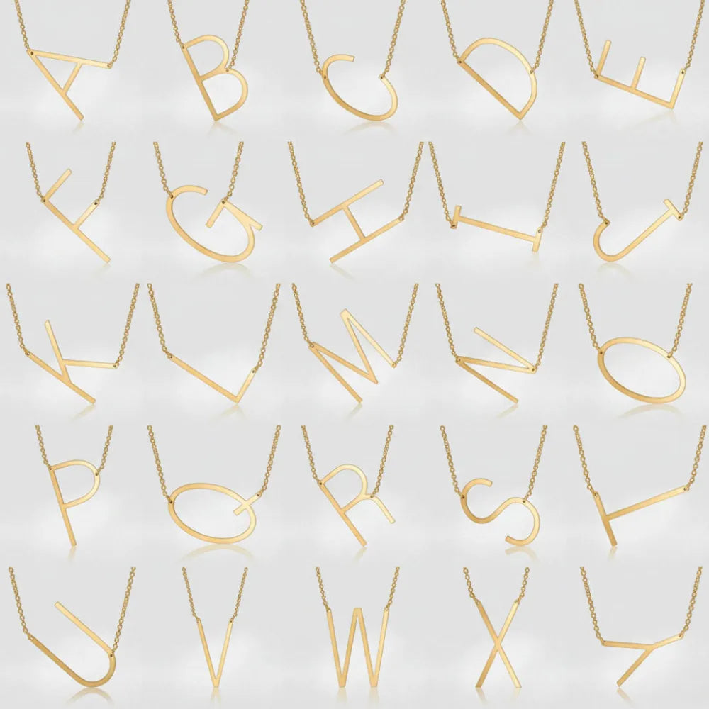 Guld färgat minimalistiskt halsband med stor bokstav och tunna kedjelänkar från juno