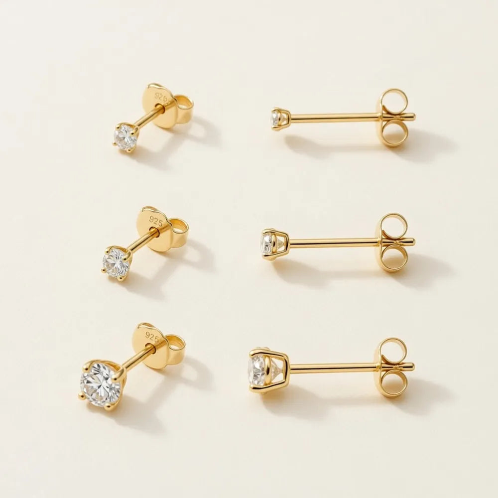 Set med sex guldfärgade örstickare allie studs i trepack med klara cubic zirkonia stenar i fyrklöverfattning