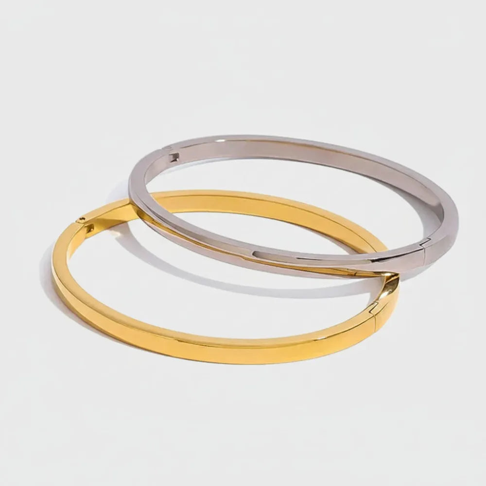 Två minimalistiska enkelt banglearmband i polerat guld och silver i slät metall med modern design