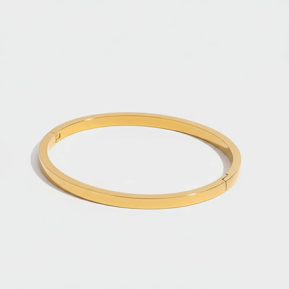 Grundläggande enkelt banglearmband i guldfärgad ton med minimalistisk design och slät polerad yta