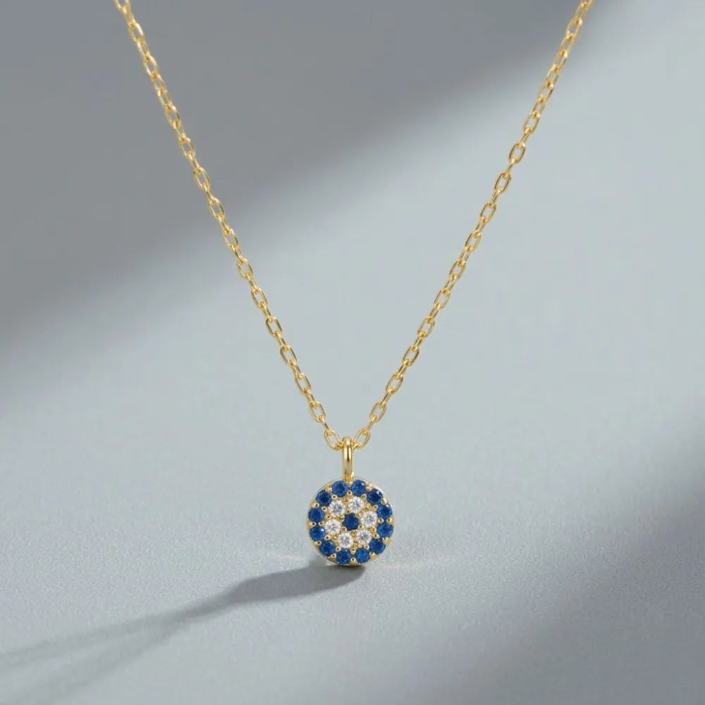 Guldhalsband med runt hänge prytt med blå och klara stenar i ett öga mönster blå eyes halsband med blå stenar