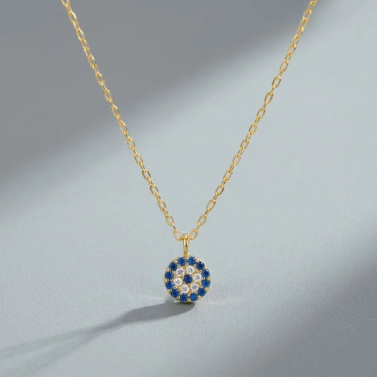 Guldhalsband med runt hänge prytt med blå och klara stenar i ett öga mönster blå eyes halsband med blå stenar