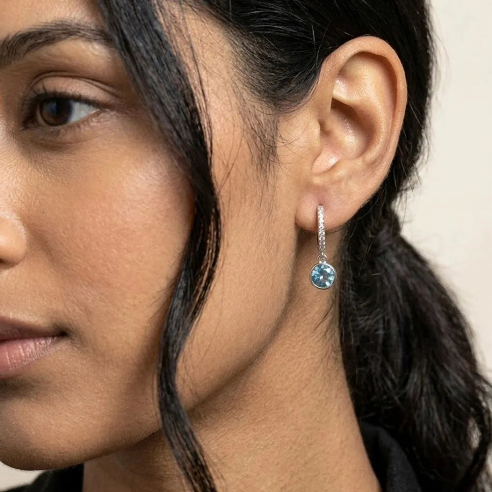 Silver hoop earring with pavé diamonds and a dangling round isblå blå gemstone from blue ivy eleganta hoops med isblå sten