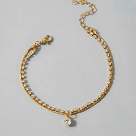 Guldtonad fotlänk med dubbla kedjor prydd med klara strass och hängande kristallpendel celia