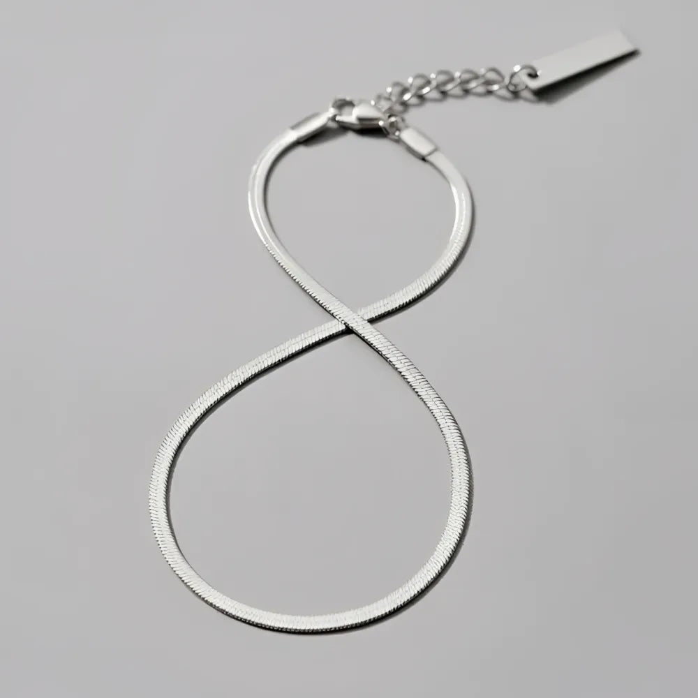 Silverinfinitetsymbol-anklet med tunnare ormbenskedja och liten rektangulär tagg vid låset, chicago fotlänk