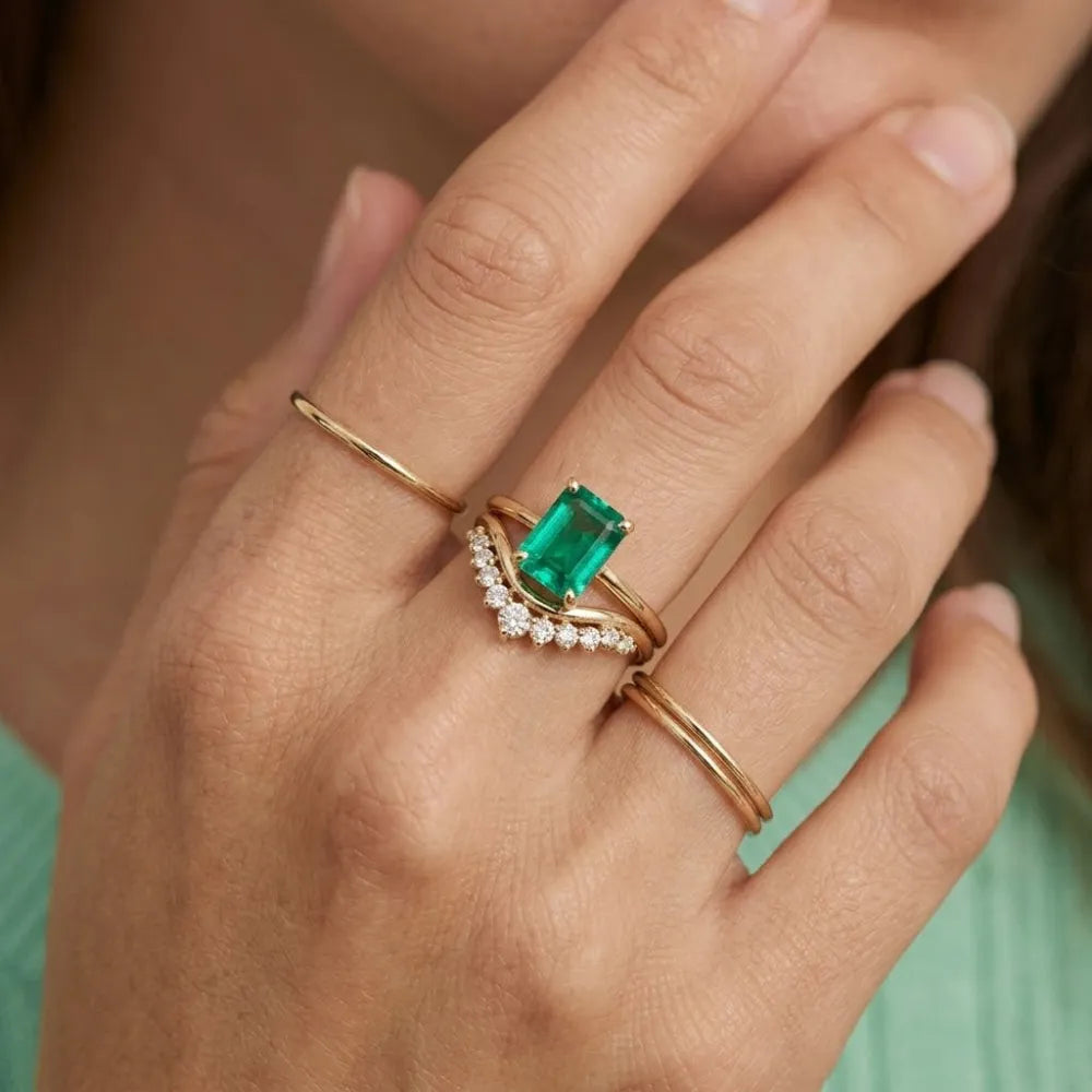 Ring kronformad med en livfull smaragdslipad grön ädelsten i en tunn guldband med diamantdetaljer