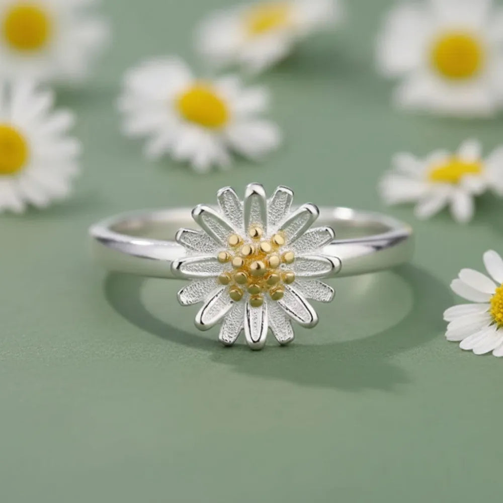 Justerbar ring daisy flower i silver med texturerade kronblad och gulddetalj mot mjuk grön bakgrund