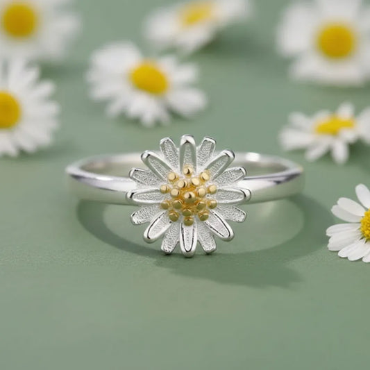 Justerbar ring daisy flower i silver med texturerade kronblad och gulddetalj mot mjuk grön bakgrund