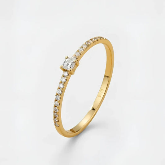 Gloria ring med liten sten i guldfärg med prinsesslipad diamant och små runda diamanter på sidan