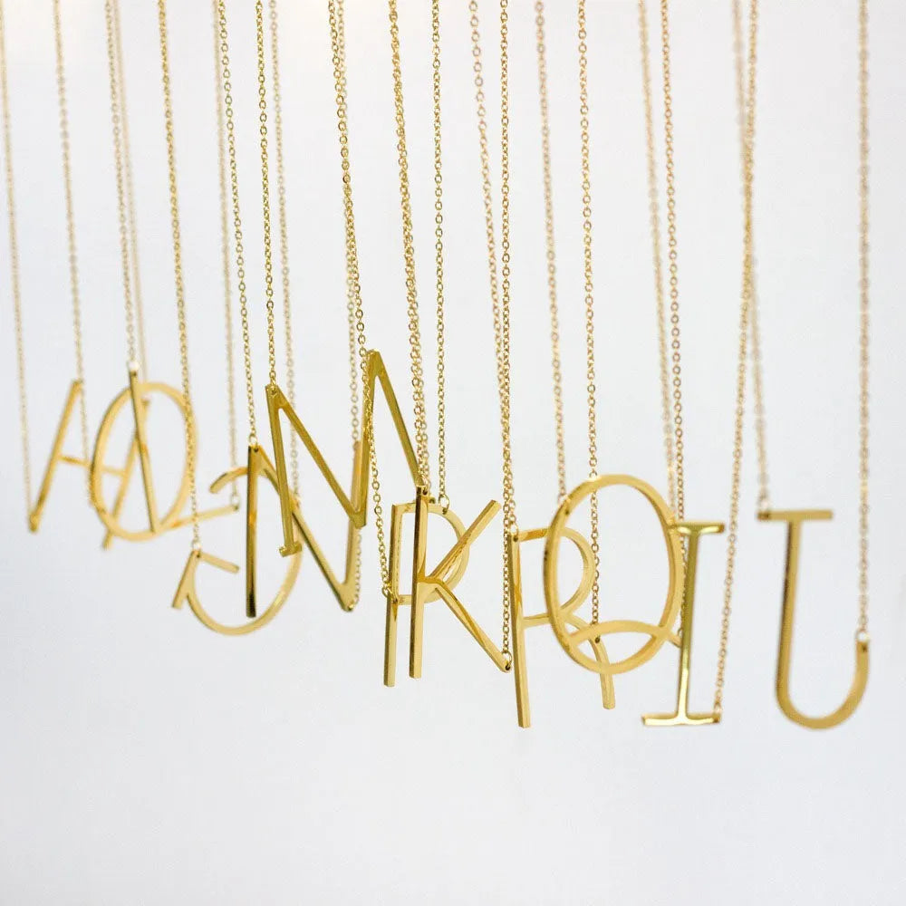 Juno halsband med stor bokstav i guld färgat minimalistiskt design på tunna kedjor