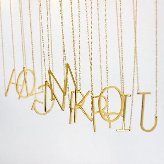 Juno halsband med stor bokstav i guld färgat minimalistiskt design på tunna kedjor