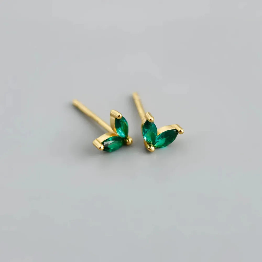 Ömtåliga gold stud earrings with two vibrant emerald green marquise stones in a minimalist leaf design