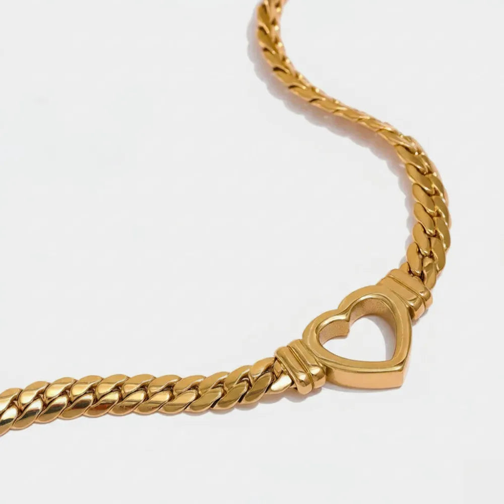 Guldtonat lovis halsband med grövre kedja och hjärtformad låsdetalj i metall