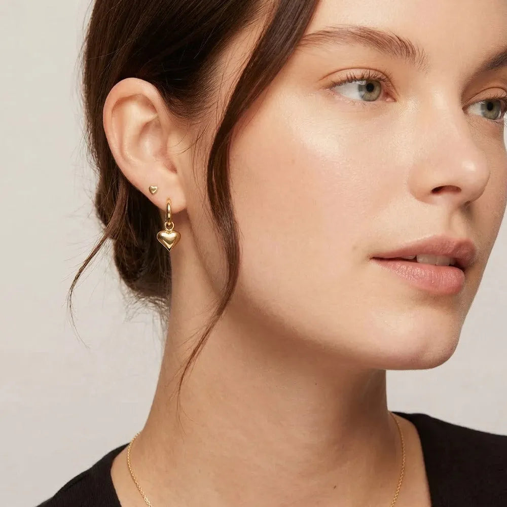 Guldfärgade hjärtformade örhängen med hängande design och små hoop-studs från luvina
