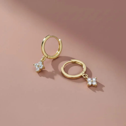 Guldiga hoopörhängen med små fyrbladiga blomcharms dekorerade med klara kristaller malva hoops med blommotiv