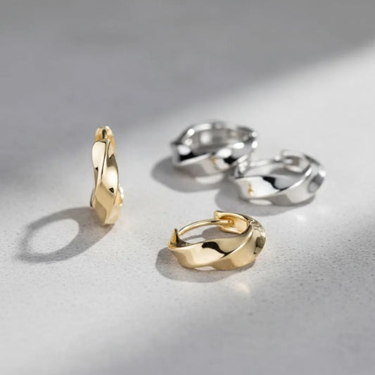 Goldtonade metall huggies med tvinnad design och modern stil