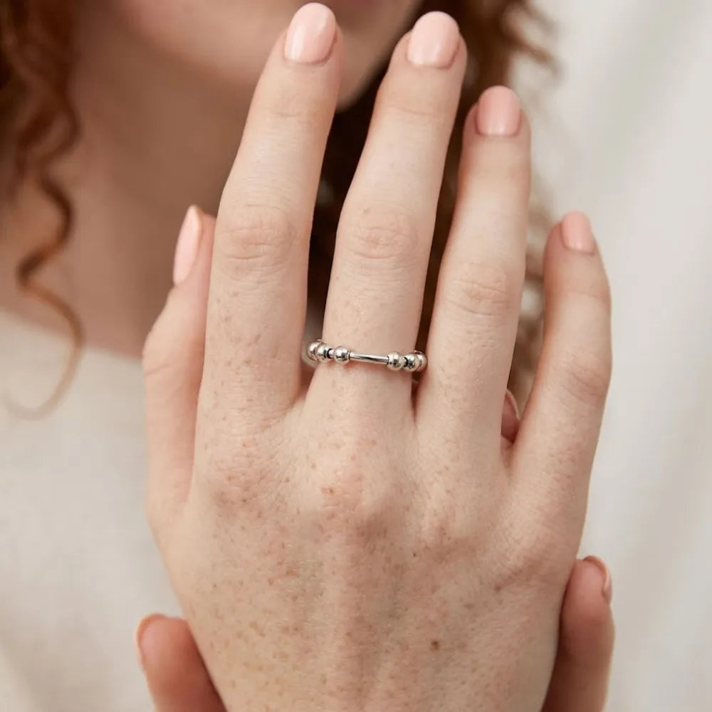 Silverfärgad antistressring med roterbara kulor och minimalistisk design i metall
