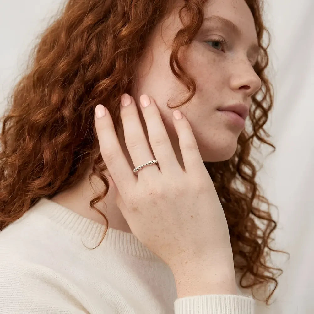 En silverfärgad antistressring med roterbara kulor pryder modellens finger