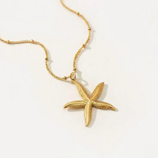 Guld stjärnformad sjöstjärnanhängare med texturerad design och fin pärlkedja nerina halsband
