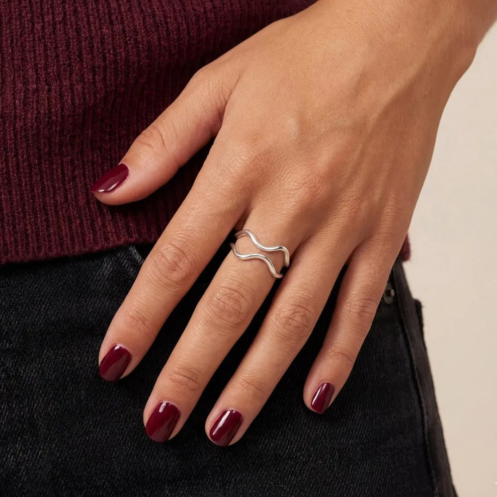 En justerbar silverring roya med en oregelbunden vågig design som pryder fingret