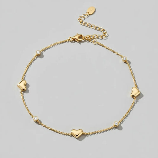 Sally fotlänk med hjärtan och stenar i guldfärgat material med tredimensionella hjärtan och små klara stenar