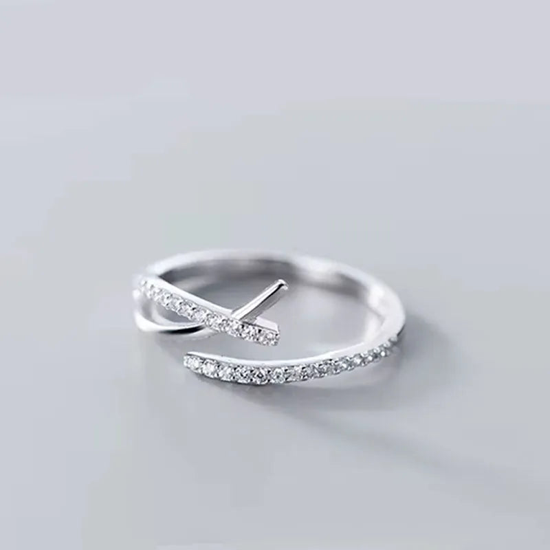 Sivra justerbar silverring med böljande form och två korsande band med små gnistrande diamanter