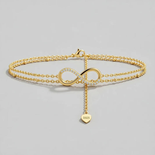Timeless fotlänk med dubbla kedjor i guld och infinitysymbol med infattade diamanter och hjärtberlock s925