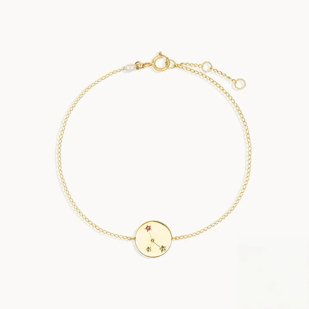 Guldtonat armband med cirkulär berlock, ingraverad stjärnteckendesign och rosa ädelstensdetalj